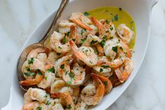 a white bowl filled with shrimp and garnished with parsley