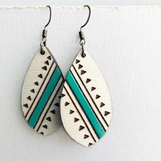 two pairs of earrings with turquoise and brown designs on them, hanging from the wall