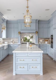 a large kitchen with blue cabinets and white counter tops, an island in the middle