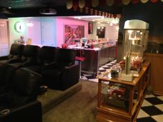 a living room filled with black couches next to a bar and checkered floor