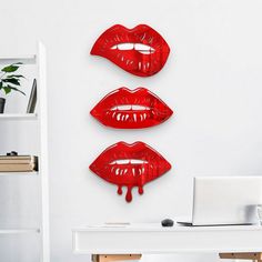 three red lips hanging on the wall next to a laptop