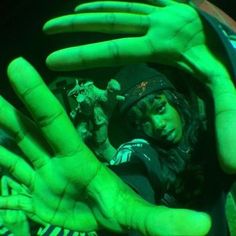 a person with their hands up in the air and green paint on her face,