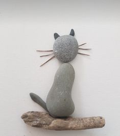 a cat made out of rocks sitting on top of a piece of drifty wood