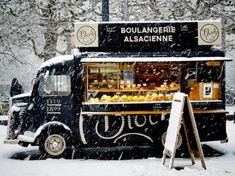 a food truck parked in the snow with it's door open and people walking by