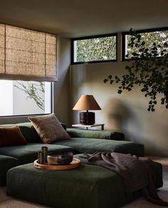 a living room with a green couch and two lamps on the side of the wall