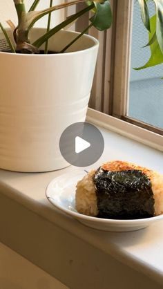 a white plate topped with sushi next to a potted plant on a window sill