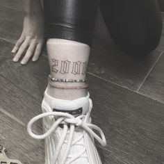 a person with tattoos on their ankle wearing white sneakers