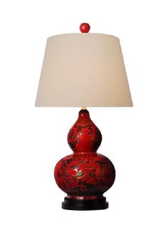 a red lamp with a white shade on it and a flowered vase in the shape of a ball