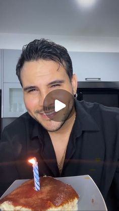 a man holding a cake with a lit candle on it in front of his face