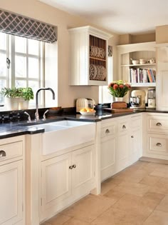 a clean kitchen with white cabinets and black counter tops is seen in this image from the front