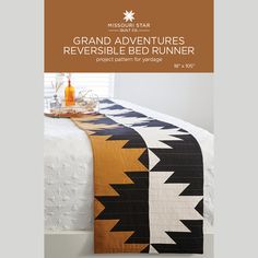 a bed with an orange and black quilt on it