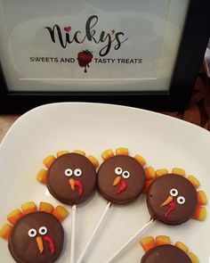 four chocolate turkey lollipops on a white plate with candy sticks in the middle