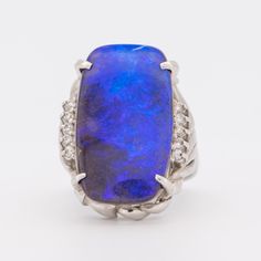 an image of a ring with a blue stone in the middle and diamonds around it