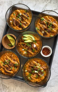 six bowls filled with food sitting on top of a tray next to an avocado