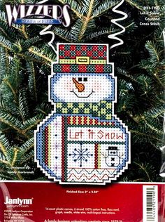 a cross stitch snowman ornament hanging on a christmas tree