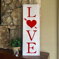 a wooden sign with the word love painted on it next to a potted plant