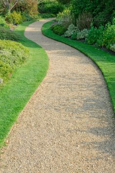 a gravel path in the middle of a lush green park