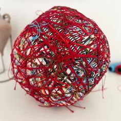 a ball of yarn sitting on top of a table next to some scissors and thread