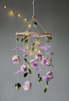 a wind chime with paper flowers hanging from it's sides and lights in the background