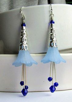 Add a touch of whimsy to any outfit with our Lucite Flower Earrings! These frosted flowers come in a beautiful blue or purple, paired with bright silver cones and sparkling crystals. Perfect for adding a pop of color and fun to your look. Lead & Nickel Free Silver Plating Measures 3 1/4 inches (approximately) in length from the very top of the ear wire Available in Blue and Purple (the purple is a richer tone than the photo depicts) Frosted Lucite Flower, Decorative Bright Silver Cones, and Faceted Purple crystals. Made in the U.S.A. Whimsical Blue Dangle Flower Earrings, Blue Whimsical Dangle Flower Earrings, Whimsical Blue Flower Earrings, Whimsical Blue Earrings For Party, Blue Flower Earrings With Ear Wire For Party, Trendy Jewelry Ideas, Frosted Flowers, Bloodstone Jewelry, Animal Themed Jewelry