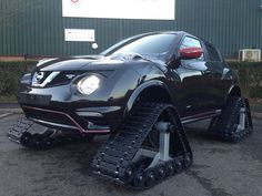 a black car with snow chains on it's front wheels and tires parked in a parking lot