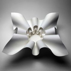 a white flower shaped object sitting on top of a gray surface with its petals open