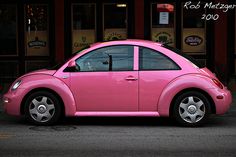 a pink car parked in front of a store