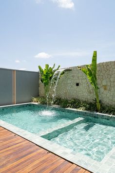 an outdoor swimming pool with wooden decking and stone walls, surrounded by greenery