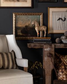 a living room with black walls and pictures on the wall, including a horse figurine