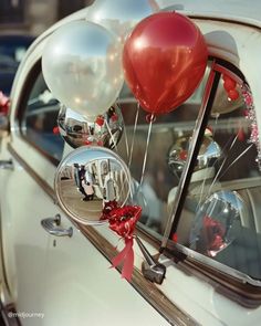 a car with some balloons in the side mirror