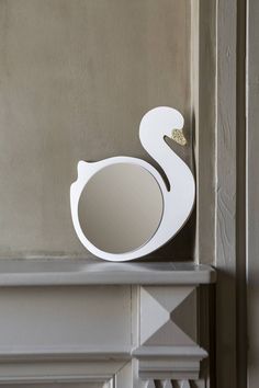 a white swan shaped mirror sitting on top of a shelf