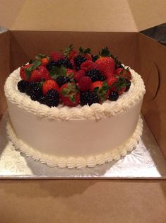 a white cake with berries on top in a box