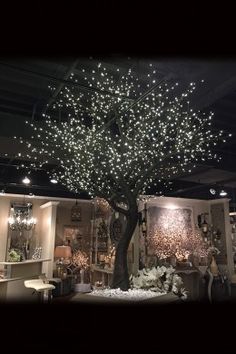 a tree is lit up in the middle of a room with many lights on it