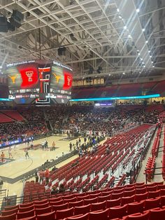 an empty basketball court with red seats and people on the sidelines looking at it