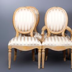 two wooden chairs with striped upholstered back and arms, side by side against a gray background