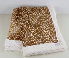 a giraffe print blanket folded on top of a table with a white wall in the background