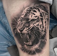 a black and white tiger tattoo on the arm with an open mouth, showing teeth