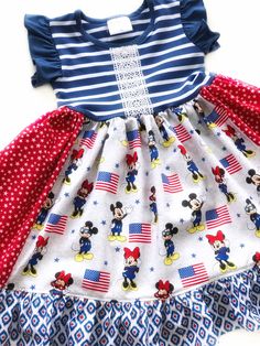 Our Main Street USA dress is fashioned in our knit flutter style bodice & a cotton ruffle skirting, perfect for wowing the crowd! Hand designed from a delightful mix of prints that please & colors that pop. Great for Magical vacations, Disney days, gift giving, theme parties, & everyday wear!All designs are tagged in the even size.12mo/18mo: 17" 2/3: 21" 4/5: 24" 6/7: 26" 8: 28" 8/10: 31” 12/14: 32”Chest width unstretched: sz 12mo/18mo: 20" 2/3: 22.5" 4/5: 23.5" 6/7: 26" 8: 28"8/10: 28” 12/14: 28” *This listing is for the dress only! Outfit options can be found in the drop down menu! Dress & pants= Dress & red/white double ruffle shorts Outfit = Dress, red/white shorts, & necklace!Ships in 2-5 days! Ruffle Shorts Outfit, Usa Dress, Patriotic Dresses, Main Street Usa, Disney Day, Theme Parties, Usa Dresses, Ruffle Shorts, Hand Designs