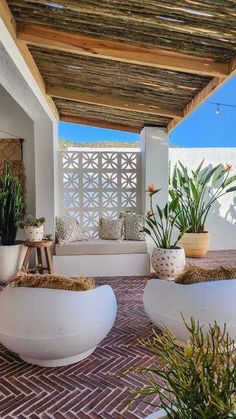 an outdoor living area with white furniture and potted plants