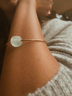 This Seaglass Banle is crafted from beautiful gold filled metal and features a round light blue sea glass bead. With its size of 6,7, or 8” this bangle is perfect for all wrist sizes. It's an eye-catching piece sure to make a statement.