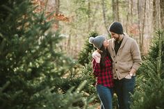 a man and woman walking through a christmas tree farm