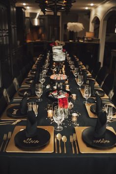 a long table is set with black and gold place settings