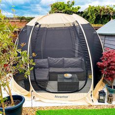 an outdoor tent is set up in the back yard with plants and potted trees