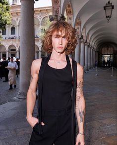 a man with tattoos standing in front of columns