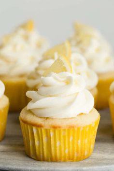 three cupcakes with white frosting and sprinkles sitting on a marble surface