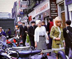 several people are walking down the street in front of some motorcycles and other motorbikes