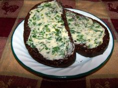 two pieces of bread with cheese and spinach spread on them sitting on a plate