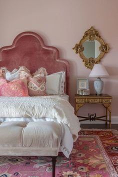 a bedroom with pink walls and an ornate headboard on the bed, along with rugs