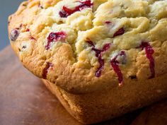 a loaf of bread with cranberry toppings on it sitting on a cutting board