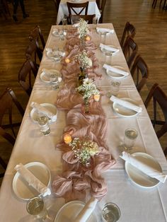 a long table is set with white plates and silverware